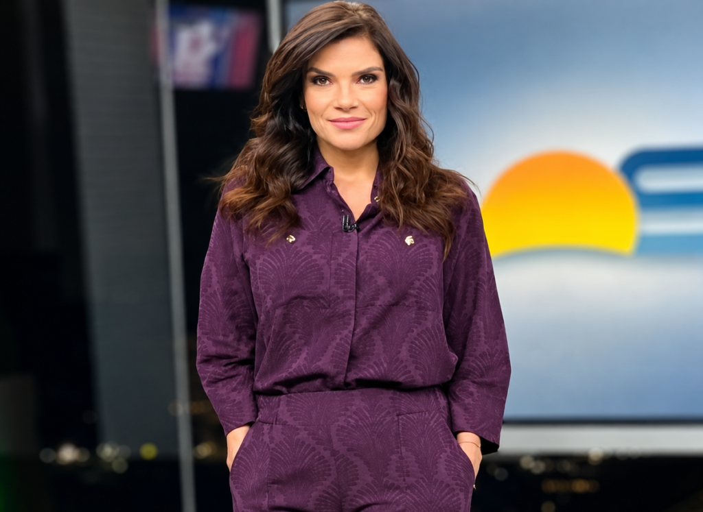 Sabina Simonato posa no estúdio do Bom Dia São Paulo, usando um conjunto roxo, diante do cenário do telejornal da TV Globo.