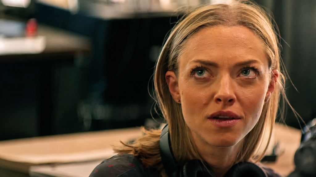 Amanda Seyfried em cena do filme A Última Palavra, observando atentamente durante uma conversa.