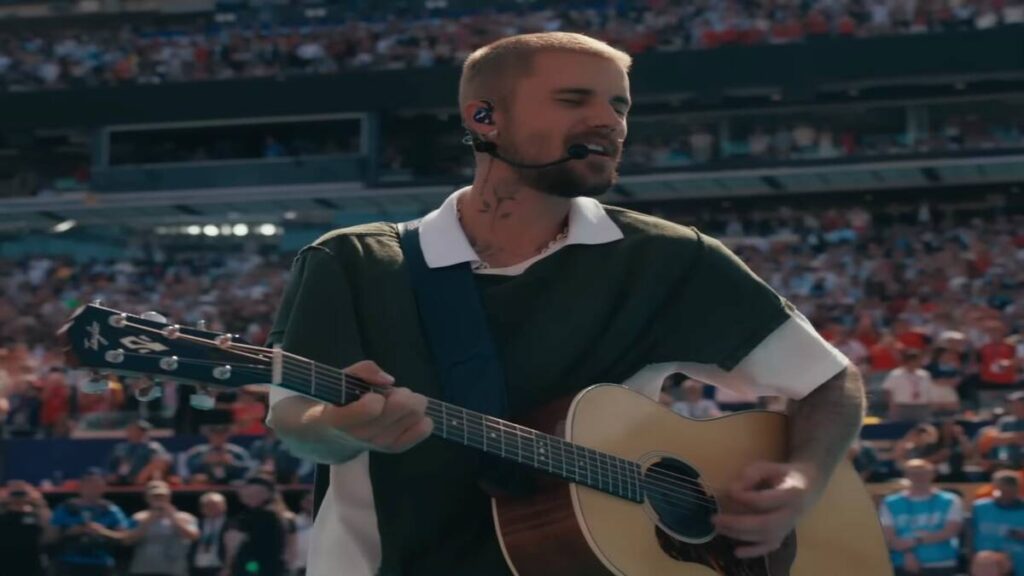 Justin Bieber canta e toca violão durante o show do intervalo da final da Copa do Mundo de 2026, realizado em um estádio lotado.