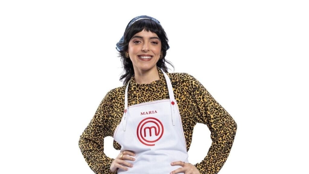 Maria posa com o avental do MasterChef Brasil 2026 após ser eliminada da competição no nono episódio do reality culinário da Band.