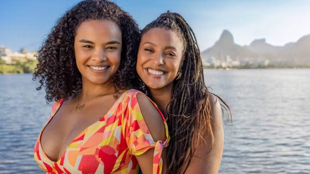 Sheron Menezzes e Lucy Ramos posam sorrindo à beira de uma lagoa durante divulgação da novela Por Você, nova produção da Globo inspirada em uma história real.